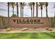 Community sign at Villages at Rancho El Dorado with desert landscaping, palm trees and a well manicured lawn at 43615 W Roth Rd, Maricopa, AZ 85138