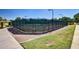 Community tennis courts with green fencing, surrounded by walking paths, landscaping, and shade structures, providing a recreational space at 43615 W Roth Rd, Maricopa, AZ 85138