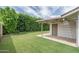 Well-maintained backyard featuring lush green grass, a covered patio, and a tall privacy hedge at 4443 W Acoma Dr, Glendale, AZ 85306