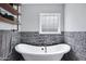 Elegant bathroom highlighting a white bathtub, stone accent wall, and glass block window at 5020 E Dallas St, Mesa, AZ 85205