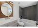 Modern bathroom featuring a bathtub with gray tiling, floating sink and gold fixtures, and a round mirror at 520 N Stapley Dr # 166, Mesa, AZ 85203