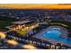 Stunning aerial view of the community pool and clubhouse illuminated at twilight, showcasing luxurious amenities and a vibrant community at 5250 S Wesley Cir, Mesa, AZ 85212