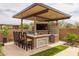 Outdoor kitchen with bar seating, stone accents, built-in grill, and beverage cooler for the ultimate entertaining experience at 5250 S Wesley Cir, Mesa, AZ 85212