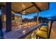 Covered outdoor kitchen with seating, stone backsplash, a linear fireplace, and a bar perfect for entertaining guests at 5250 S Wesley Cir, Mesa, AZ 85212
