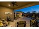 Covered patio overlooking a sparkling pool, outdoor kitchen area, and lush landscaping, creating a private oasis at 5250 S Wesley Cir, Mesa, AZ 85212