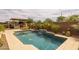 Inviting pool featuring a built-in waterfall, tanning ledge, and nearby outdoor kitchen and umbrella-shaded lounge chairs at 5250 S Wesley Cir, Mesa, AZ 85212
