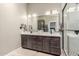 Bathroom featuring double sink vanity, white countertops, dark wood cabinets, and a glass-enclosed shower at 6357 W Potter Dr, Glendale, AZ 85308