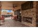 Covered patio featuring an outdoor stone fireplace, ceiling fan, and comfortable seating at 6357 W Potter Dr, Glendale, AZ 85308