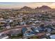 Scenic aerial view of a residential neighborhood with views of rocky mountains against a colorful sunset sky at 6450 E Vernon Ave, Scottsdale, AZ 85257