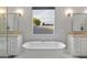 Spa-like main bathroom featuring a soaking tub, dual vanities, and a large window with natural light at 6450 E Vernon Ave, Scottsdale, AZ 85257