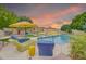 Inviting pool area featuring comfortable lounge chairs, umbrellas, and lush landscaping under a vibrant sunset sky at 700 N Dobson Rd # 34, Chandler, AZ 85224