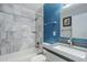 Well lit bathroom showcasing marble tiled shower and modern vanity with stone countertop at 7135 W Flower St, Phoenix, AZ 85033