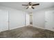 Neutral bedroom featuring gray carpet, white walls, ceiling fan, and three doors at 7135 W Flower St, Phoenix, AZ 85033