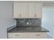 This kitchen showcases white cabinets with gray quartz countertops and a mosaic backsplash at 7135 W Flower St, Phoenix, AZ 85033