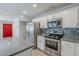 Bright kitchen boasts stainless steel appliances, white cabinetry, mosaic backsplash and red door at 7135 W Flower St, Phoenix, AZ 85033
