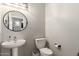 A compact powder room with a pedestal sink, toilet, and decorative mirror at 7385 W Honeysuckle Dr, Peoria, AZ 85383