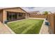 Backyard with synthetic grass, brick border, rock features and covered patio with seating providing a perfect space to relax at 9757 E Red Giant Dr, Mesa, AZ 85212