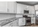 Close-up view of the kitchen with granite counters, white cabinets, and stainless steel oven and microwave at 9757 E Red Giant Dr, Mesa, AZ 85212