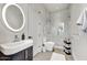 Contemporary bathroom featuring a sleek vanity, round mirror, and walk-in shower with vertical tiling at 9939 E Desert Jewel Dr, Scottsdale, AZ 85255