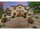 Beautiful home exterior with a stone entryway, arched windows, and meticulously landscaped front yard at 9939 E Desert Jewel Dr, Scottsdale, AZ 85255