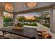 Covered patio with an elegant dining area overlooking a pristine pool and beautifully landscaped backyard with mountain views at 9939 E Desert Jewel Dr, Scottsdale, AZ 85255