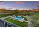 Inviting pool area with luxurious lounge chairs, lush landscaping, and beautiful mountain views at dusk at 9939 E Desert Jewel Dr, Scottsdale, AZ 85255