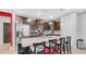 Open kitchen features dark cabinets, stainless steel appliances, island with seating, and pendant lighting at 11742 W Chase Ln, Avondale, AZ 85323