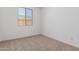 A bright, carpeted bedroom with a view from a large window at 12381 W Marguerite Ave, Avondale, AZ 85323