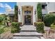 Elegant entry with arched doorway, wrought iron door, pendant lights, and stone steps amid lush landscaping at 13250 N 13Th Ln, Phoenix, AZ 85029