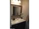 Well-lit bathroom with a decorative mirror, speckled countertop, and dark wood vanity at 13486 W Evans Dr, Surprise, AZ 85379