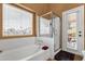 Bright bathroom featuring a soaking tub, glass-enclosed shower, and an exterior access door at 1558 W Maplewood St, Chandler, AZ 85286