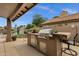 An outdoor kitchen with a built-in BBQ and mini-fridge and seating that overlooks the water at 1558 W Maplewood St, Chandler, AZ 85286
