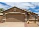 Close-up view of the two-car garage, showing the front entryway and desert landscaping at 15980 W Smokey Dr, Surprise, AZ 85374
