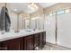 Bright bathroom with double sinks, dark wood cabinets, and a glass-enclosed shower at 17111 S 180Th Ln, Goodyear, AZ 85338