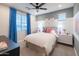 Inviting bedroom with bright blue curtains, white bedding, and colorful artwork, creating a cheerful atmosphere at 17245 W Corrine Dr, Surprise, AZ 85388