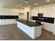 Bright kitchen features white cabinetry, black countertops, and large island at 17245 W Corrine Dr, Surprise, AZ 85388