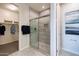 Bathroom with a walk-in closet and a glass enclosed shower featuring decorative tile and modern fixtures at 17312 W Dahlia Dr, Surprise, AZ 85388