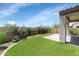 Private backyard featuring lush artificial grass, bougainvillea bushes, and a covered patio at 1847 N Red Clf, Mesa, AZ 85207
