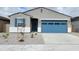 Charming single-story home with blue door, gray stone and a blue garage door at 19422 N Fiano Dr, Maricopa, AZ 85138