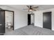 Bedroom features gray carpet, white walls, a ceiling fan and views into the bathrooms and closet at 3011 E John Cabot Dr, Phoenix, AZ 85032