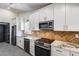 Modern kitchen with stainless steel appliances, white cabinets, granite countertops, and herringbone backsplash at 3011 E John Cabot Dr, Phoenix, AZ 85032
