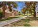 Exterior view featuring a sidewalk, green space, and multi-story condos surrounded by mature trees at 3491 N Arizona Ave # 118, Chandler, AZ 85225