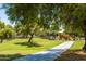 Lush park with walking path, mature trees, and a playground in the distance at 3605 W Pecos Rd, Chandler, AZ 85226