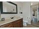 Bathroom with a dark vanity, decorative mirror, and stylish wood-look tile flooring at 3812 W Carlos Ln, San Tan Valley, AZ 85144