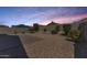 Large backyard with gravel, lush green bushes, and a brick-paved patio area during sunset at 4218 W Palace Station Rd, New River, AZ 85087