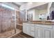 Stylish bathroom with a walk-in shower featuring brown tiling, granite counters, and double sinks at 4218 W Palace Station Rd, New River, AZ 85087