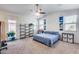 Bedroom featuring neutral carpet, a ceiling fan, bright windows, shelving, and a queen bed at 4218 W Palace Station Rd, New River, AZ 85087