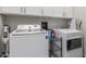 Laundry room featuring a front load washer, dryer, and ample storage space at 4446 W Kimberly Way, Glendale, AZ 85308