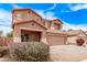 Two-story home boasts a two-car garage, a cozy front porch and colorful flowering bushes at 45574 W Tulip Ln, Maricopa, AZ 85139