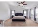 Bright main bedroom showcasing a bed, ceiling fan, and natural light from surrounding windows at 45574 W Tulip Ln, Maricopa, AZ 85139